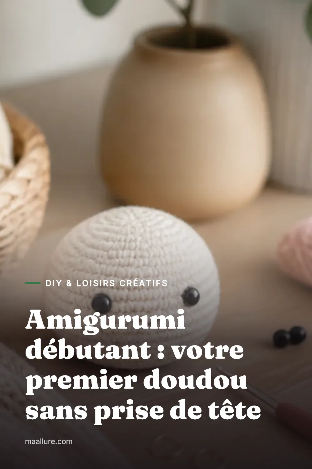 Petit doudou amigurumi rond en crochet posé sur une table en bois à côté d'une pelote de coton et d'un crochet