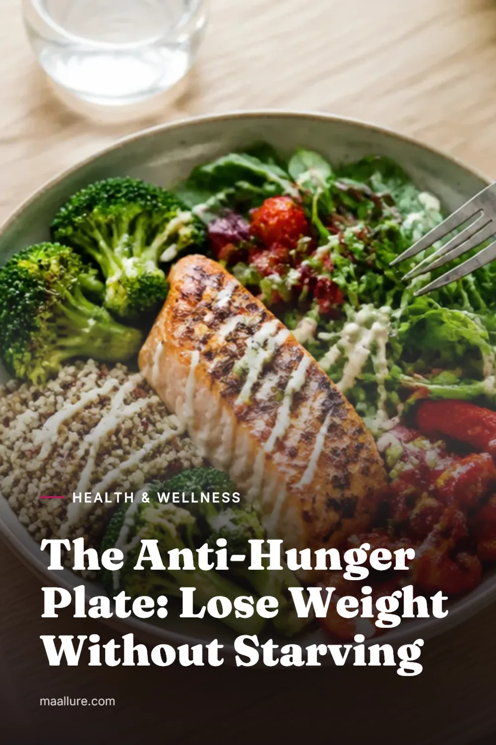 Overhead view of a filling lunch bowl with salmon, roasted vegetables, leafy greens and quinoa, with berries and a glass of water on a wooden table